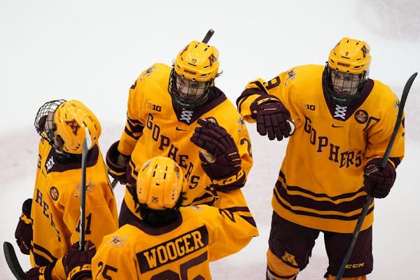 Gophers forward Blake McLaughlin (27) was congratulated by his teammates after he scored the game-winning goal against Bemidji State on Saturday night