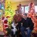 Kevin Milton, right, with his partner Bill Emery and their dog Maximus Spartacus, pose for a photo in front of trees in their living room.