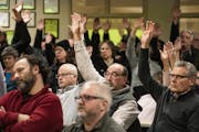 Those who approved a motion to refuse refugee resettlement raised their hands in the overcapacity crowd in attendance earlier this month in Minnesota'