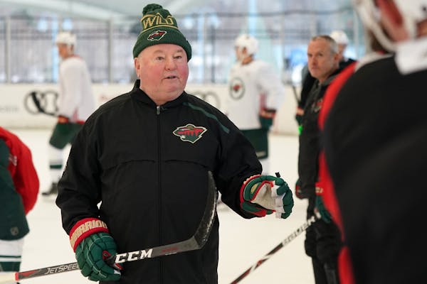 Wild head coach Bruce Boudreau talked with players along the boards during the team's outdoor practice on Jan. 1