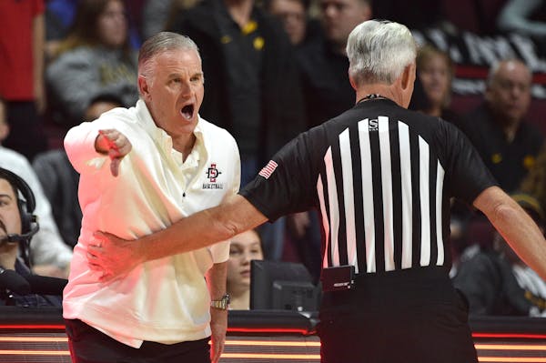 San Diego State coach Brian Dutcher is held back by a referee as he calls to his team during the first half against Iowa on Nov. 29