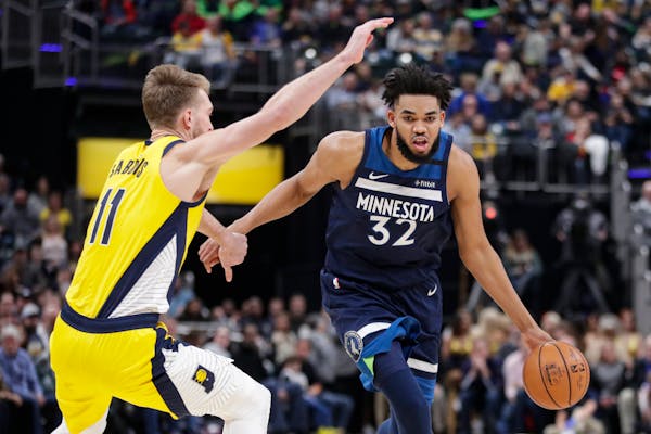 Timberwolves center Karl-Anthony Towns drives around Pacers forward Domantas Sabonis