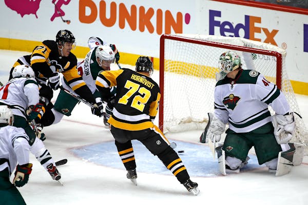 Pittsburgh's Evgeni Malkin (71) puts the puck behind Wild goaltender Devan Dubnyk with Jared Spurgeon defending for a goal during the first period