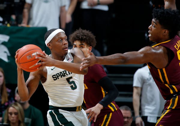 Michigan State's Cassius Winston is pressured by Minnesota's Marcus Carr during the first half