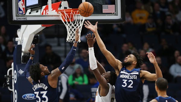 The Timberwolves' Karl-Anthony Towns reaches up to rebound the ball over Denver's Torrey Craig