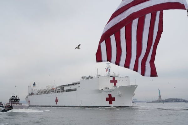 The USNS Comfort, with the Statue of Liberty in the background, arrives in New York, Monday morning, March 30, 2020. The Navy hospital ship is expecte