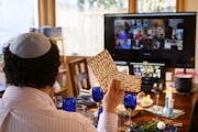 Bruce Manning held up matzo, which he just broke in half as part of Passover seder ritual, as he took part in a virtual seder alongside his family Wed