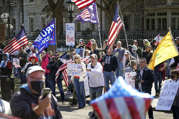 Hundreds of protesters gather outside Minnesota Gov. Tim Walz' official residence, Friday, April 17, 2020 in St. Paul, Minn. President Donald Trump tw