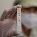 An employee holds up an antibody test cartridge from an ichroma COVID-19 Ab testing kit on a production line in Chuncheon, South Korea, on April 17, 2