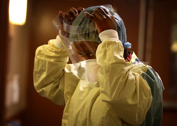 Syndie Pascal, an RN, donned personal protective equipment before checking a COVID-19 patient at Bethesda Hospital. [Credit: DAVID JOLES • Star Trib