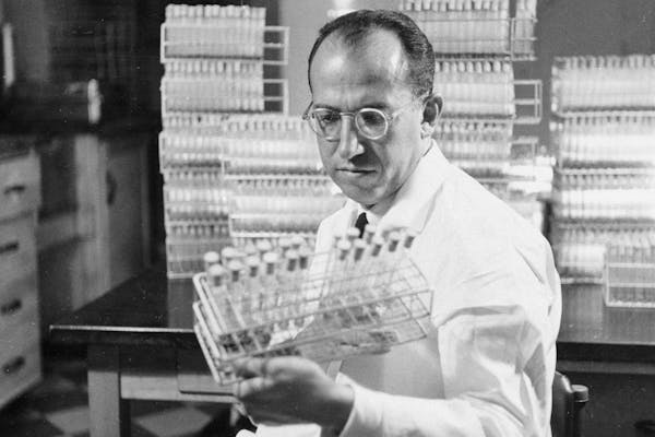 In this Oct. 7, 1954, photo, Dr. Jonas Salk, developer of the polio vaccine, held a rack of test tubes in his lab in Pittsburgh.