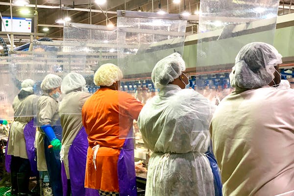 Tyson Foods workers wear protective masks and stand between plastic dividers at a poultry processing plant in Camilla, Ga. Tyson has added the plastic