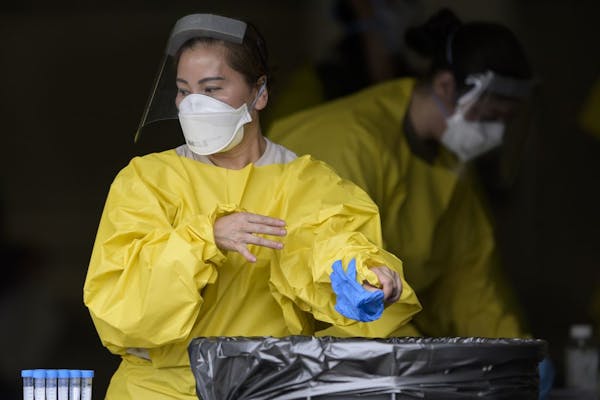 Elizabeth Santoro, a medic with the Minnesota Air National Guard 133rd Medical Group, tossed her gloves after administering a COVID-19 test Saturday a