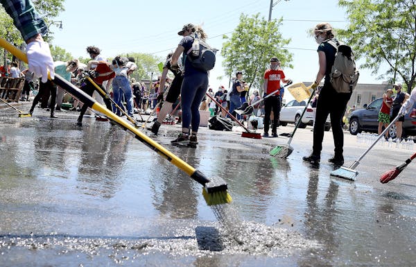 A small army of community members and volunteers work Saturday to clear water and debris outside 27 Avenue Cafe, just off of Lake Street, damaged by a