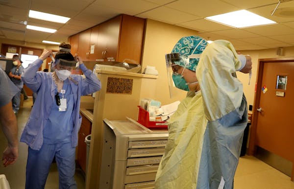 Healthcare workers don PPE before phoning a COVID-19 patient in an ICU at Bethesda Hospital Thursday, May 7, 2020, in St. Paul, MN.] DAVID JOLES • d