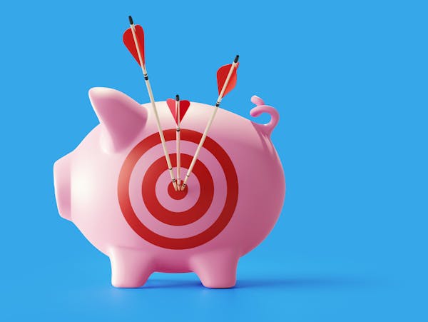 Piggy bank with bulls eye target and red arrows standing on blue background. Horizontal composition with copy space. Great use for financial concepts.