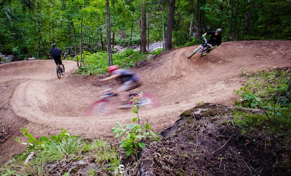 Mountain bikers careen down the Happy Camper trail at Spirit Mountain Bike Park in Duluth.