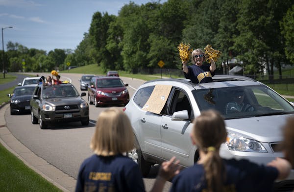 Glendale Elementary School teacher Karla Schutz waved to students who lined streets in their neighborhoods as staffers drove down the streets of Savag