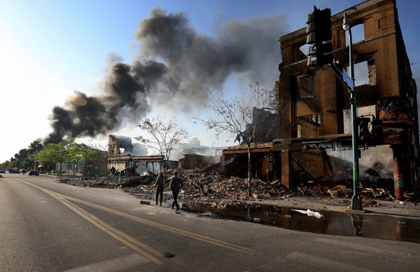 People surveyed the damage along Lake St. near S. 27th Avenue as a fire burned to the east May 30, 2020, in Minneapolis.