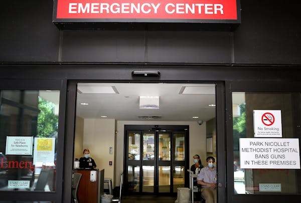 Screeners wait inside the entrance to Park Nicollet Methodist Hospital emergency room, where they check those arriving for COVID symptoms before deter