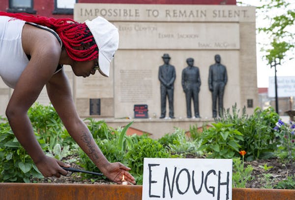 Quita Leach lit candles in front of the Clayton Jackson McGhie Memorial on Wednesday evening in Duluth.
