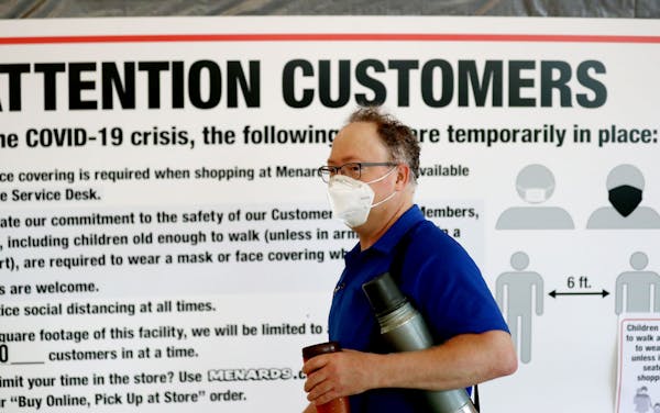 An employee walks by a sign alerting shoppers to the COVID-19 protocol at Menards in Maplewood recently. [Credit: DAVID JOLES, Star Tribune]