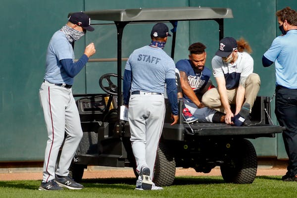 (From left) Twins manager Rocco Baldelli and coach Tony Diaz watched as assistant athletic trainer Matt Biancuzzo steadied the ankle of center fielder