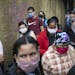 Pedestrians and commuters wearing face masks crowd a sidewalk in Caracas, Venezuela.