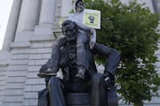 A person sits on a statue of Abraham Lincoln in San Francisco on June 13 at a protest over the death of George Floyd.