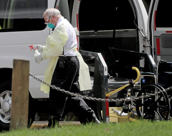 A worker with a bottle of disinfectant outside the North Ridge Health and Rehab nursing home in New Hope in July.