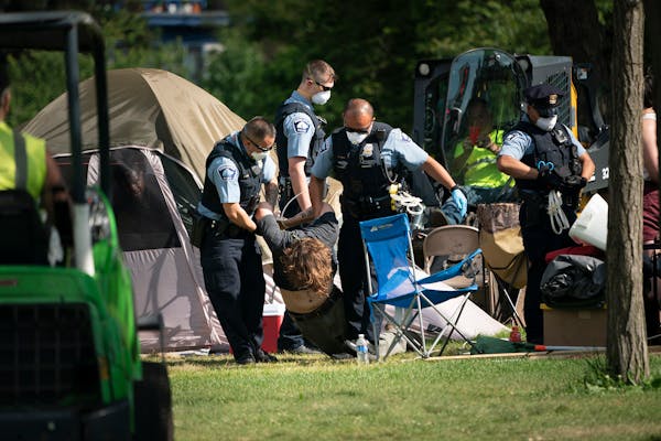 Police dragged a person from a tent as they cleared tents and possessions from the east side homeless encampment at Powderhorn Park in Minneapolis on 