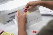 Todd Gallagher prepares mail-in ballot envelopes including an "I voted" sticker in Minneapolis in July. Absentee ballots are being requested at a reco