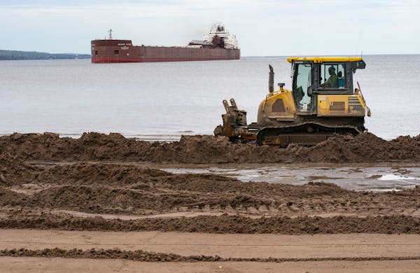 The Mesabi Miner pulled into Duluth Harbor on Tuesday as a bulldozer pushed dirt along Park Point as part of an effort to raise the beachfront.