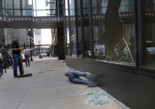 Tom Stellar, a pastor at Bethlehem Baptist Church, looked up at broken windows while cleaning up damage outside Nordstrom Rack at the IDS Center in Mi