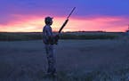 Wildlife photographer and outdoors writer Bill Marchel of Fort Ripley, Minn., is silhouetted by the rising sun near Little Falls on Tuesday morning, o