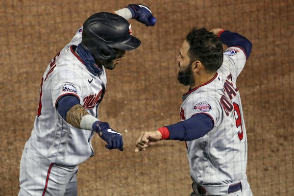 The Twins’ Eddie Rosario, left, celebrates with Marwin Gonzalez, right, after hitting a solo home run off Cubs starting pitcher Alec Mills during th