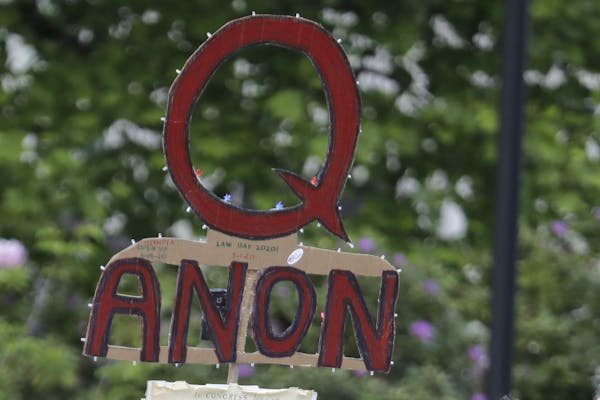FILE - In this May 14, 2020 file photo, a person carries a sign supporting QAnon at a protest rally in Olympia, Wash.