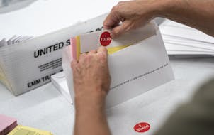 FILE - In this July 29, 2020, file photo, mail in ballot envelopes including an I Voted sticker are prepared in Minneapolis. Nevada's new vote-by-mail