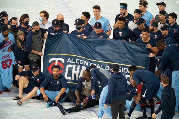 Twins players gathered on the field for a team photo with the AL Central championship banner.