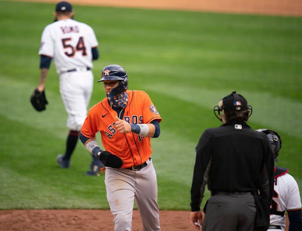 The Astros Yuli Gurriel scored after Minnesota Twins relief pitcher Sergio Romo (54), rear, walked Houston Astros second baseman Jose Altuve (27) with