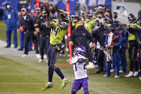 Seattle Seahawks' DK Metcalf (14) pulls in a long pass reception on the Seahawks' last series of an NFL football game as Minnesota Vikings' Cameron Da