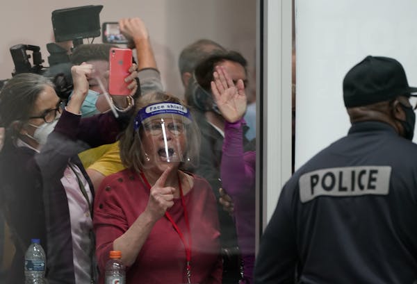 Election challengers yell as they look through the windows of the central counting board as police were helping to keep additional challengers from en