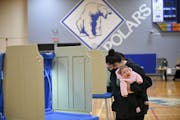 Alycia Howard, 22, of north Minneapolis, held her yawning 3-month old daughter, Alivia, as she filled out her ballot in North High School’s gymnasiu
