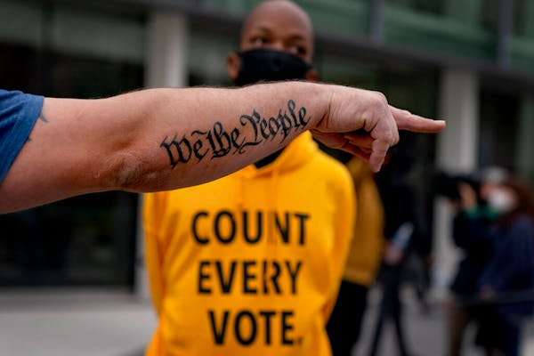 The tattoo "We the People," a phrase from the U.S. Constitution, decorates the arm of Trump supporter Bob Lewis as he argues with counterprotestor Ral