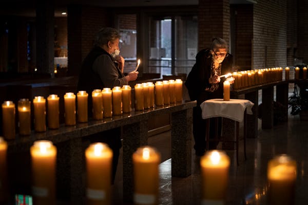 Left to right, Jodi Sandlin lit some of the more than 100 candles for loved ones of parish members who have died as Cece Ryan lit a candle in remembra
