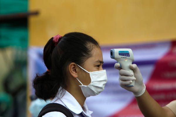 A student has her temperature checked before she enters the Santhormok high school in Phnom Penh, Cambodia, Monday, Nov. 2, 2020.