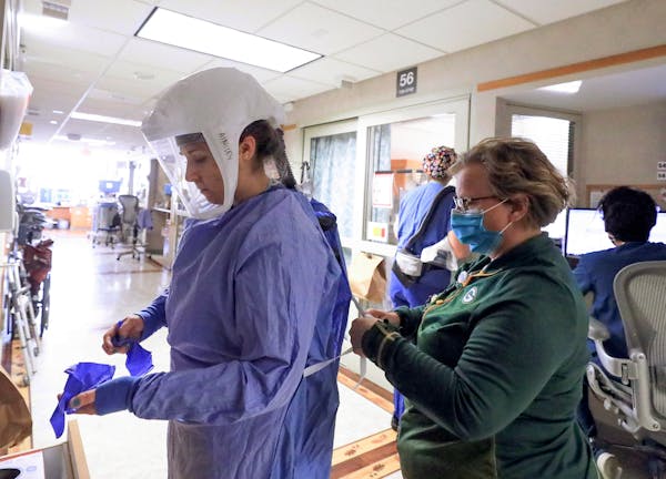 Deb Dalsing, nurse manager of the COVID-19 treatment unit at UW Health, assists nurse Ainsley Billesbach with her personal protective equipment at the