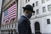 A man wearing a mask passes the New York Stock Exchange, Nov. 16, 2020, in New York.