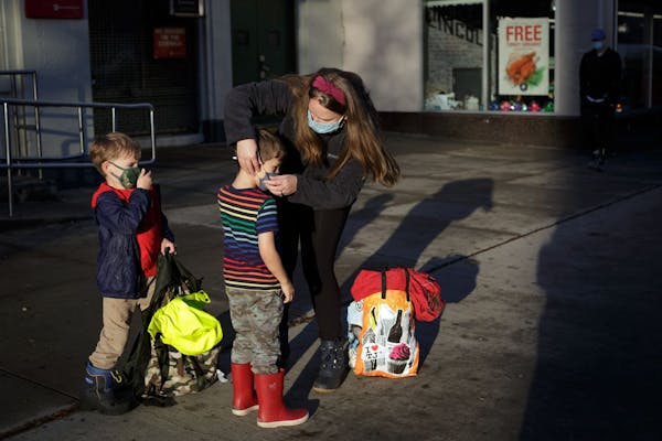 Kristy Etheridge adjusts the face masks on her son Noah, 4, left, and friend Ollie Hallock, 5, in Brooklyn on Nov. 13, 2020.