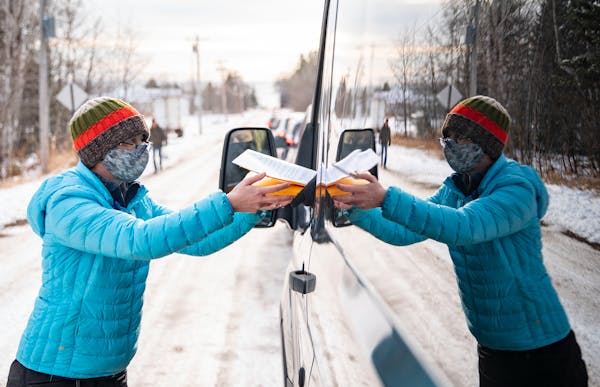 Andrea Orest walked along a line of cars in Grand Marais to hand out free at-home COVID-19 saliva tests on Dec. 16.